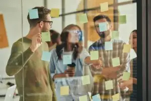 Smart and talented young people putting sticky notes on wall
